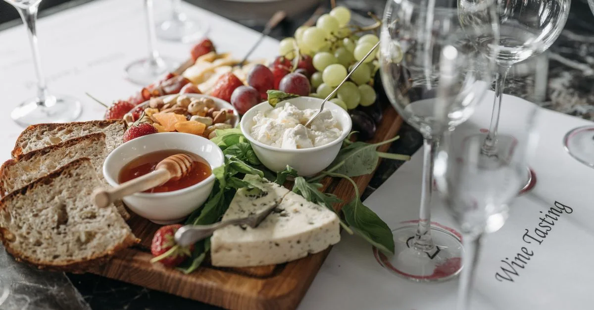 Un délicieux assortiment de fromages, fruits et pain sur une planche de charcuterie, prêt pour une dégustation de vin.